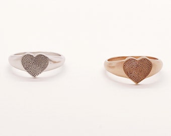 May include: Two fingerprint heart rings, one in silver and one in rose gold.
