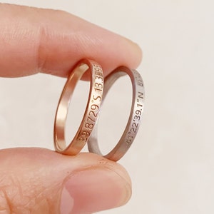 May include: Two thin gold and silver rings with engraved coordinates. The gold ring has the coordinates "39.8729°S 13.3395°E" and the silver ring has the coordinates "41°22'39.1"N 81°18'48.8"W".