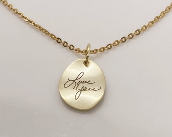 Puede incluir: Un collar de cadena dorada con un colgante redondo que dice "Love You" en escritura cursiva.