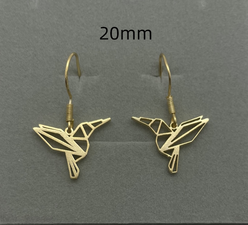 May include: A pair of gold-toned hummingbird earrings with a geometric design. The earrings are 20mm in length.