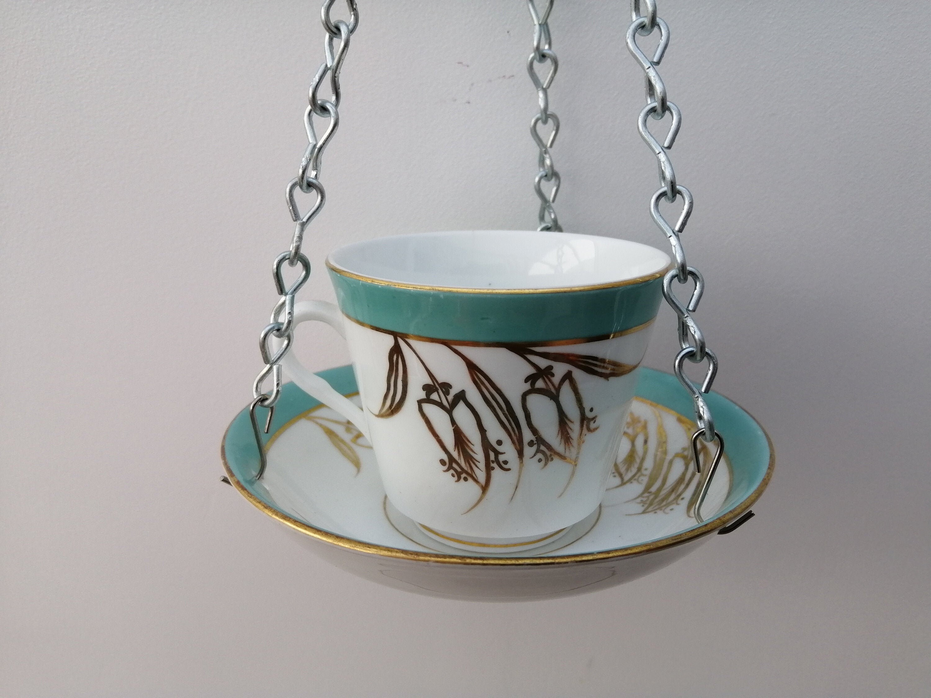 Lovely turquoise and gold ceramic indoor/outdoor hanging basket/planter. Made from a vintage tea cup and saucer with gold floral motif.