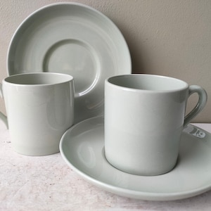 May include: Two light green ceramic coffee cups and saucers. The cups have a simple design and are perfect for everyday use.