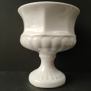 May include: White ceramic planter with a fluted design and a pedestal base.