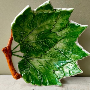 May include: A ceramic serving dish shaped like a green grape leaf with a brown stem handle.