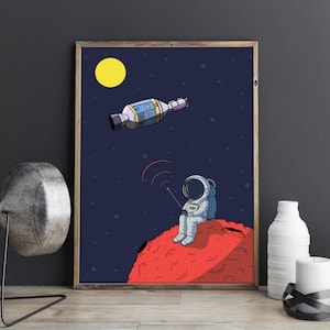 Puede incluir: Ilustraci&oacute;n enmarcada de un astronauta sentado en un planeta rojo, sosteniendo un dispositivo con ondas de radio. Una nave espacial y una luna amarilla est&aacute;n en el cielo azul oscuro estrellado. La obra de arte tiene un estilo de dibujos animados y un marco de madera.