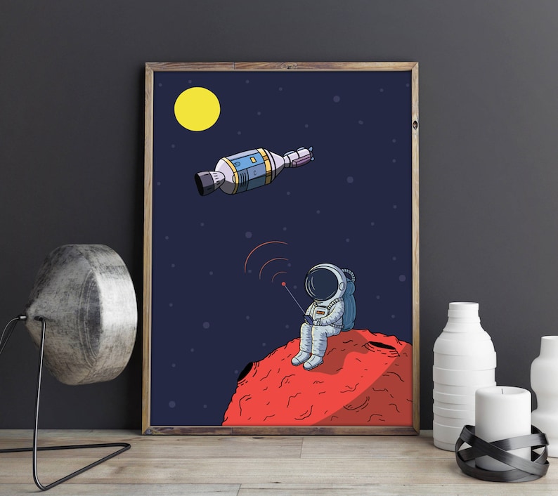 Puede incluir: Ilustraci&oacute;n enmarcada de un astronauta sentado en un planeta rojo, sosteniendo un dispositivo con ondas de radio. Una nave espacial y una luna amarilla est&aacute;n en el cielo azul oscuro estrellado. La obra de arte tiene un estilo de dibujos animados y un marco de madera.
