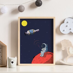 Puede incluir: Ilustraci&oacute;n enmarcada de un astronauta sentado en un planeta rojo, comunic&aacute;ndose con una nave espacial. La obra presenta un sol amarillo, estrellas y un dise&ntilde;o detallado de la nave espacial, todo sobre un fondo azul oscuro. El marco es de madera clara.