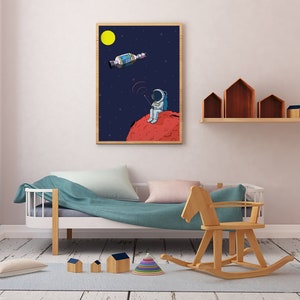 Puede incluir: Ilustraci&oacute;n enmarcada de un astronauta en un planeta rojo, sosteniendo un dispositivo con una se&ntilde;al, con un sat&eacute;lite en el espacio. El fondo es azul oscuro con estrellas y una luna amarilla. La obra de arte est&aacute; en un marco de madera.
