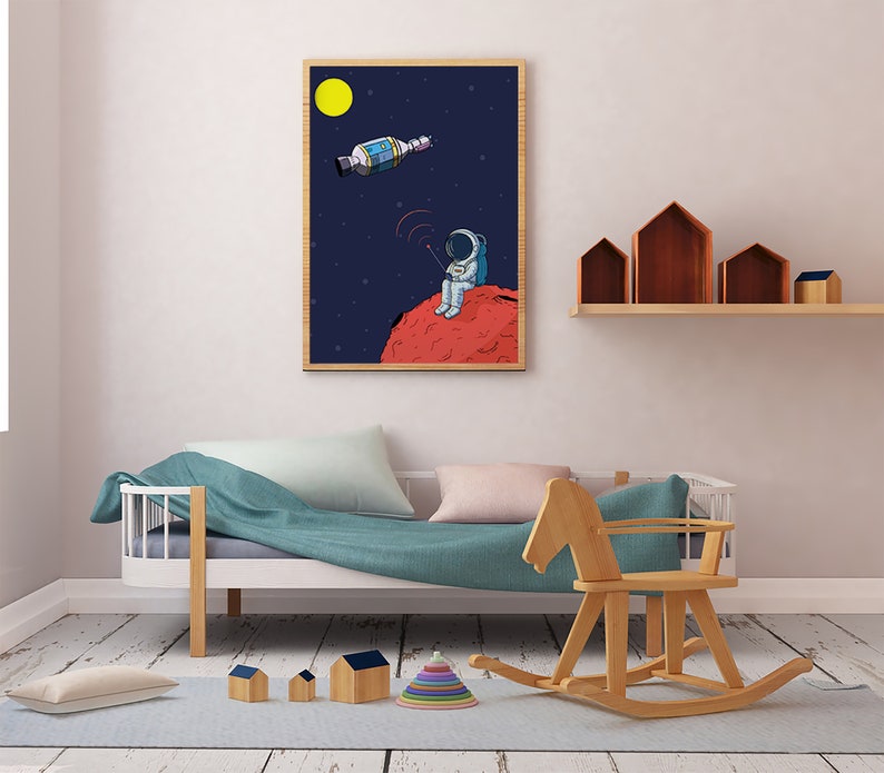 Puede incluir: Ilustraci&oacute;n enmarcada de un astronauta en un planeta rojo, sosteniendo un dispositivo con una se&ntilde;al, con un sat&eacute;lite en el espacio. El fondo es azul oscuro con estrellas y una luna amarilla. La obra de arte est&aacute; en un marco de madera.