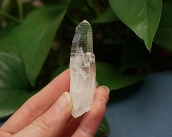 May include: A clear quartz crystal point with a double termination. The crystal is about 2 inches long and has a natural, raw appearance.
