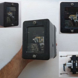 May include: A black electrical relay with a clear plastic cover. The relay has a dial with the text "ELEK. TOKH 520/2 380/220 50Hz 10Hz 0.1A 2.8A" printed on it. The relay has four terminals on the bottom.