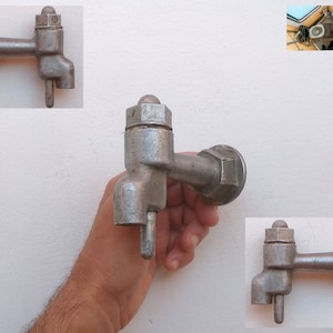 Puede incluir: Un grifo de metal plateado con una manija redonda y un caño. El grifo está montado en una pared blanca.