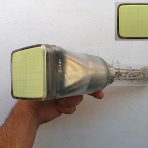 Puede incluir: Un tubo de rayos catódicos (CRT) vintage con una pantalla rectangular con patrón de cuadrícula. El tubo de vidrio tiene un cuerpo cilíndrico y una estructura interna compleja. La pantalla muestra un tono amarillo-verdoso. El texto "OTK 47" es visible.