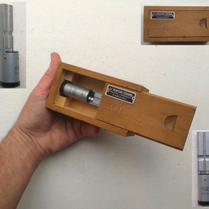 May include: A silver metal measuring tool in a wooden box with a label that reads "SL. WLADYSLAW LEDWONIEWSKI WARSZAWA No. 1127".