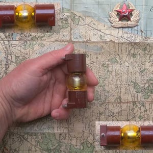 Può includere: Tre componenti elettrici vintage in vetro marrone e giallo con una lampadina in vetro trasparente. I componenti sono su una mappa con una stella rossa.