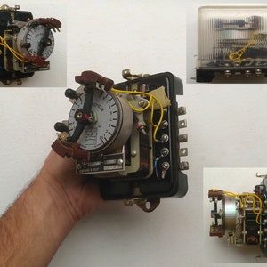 May include: A black electrical timer with a white face and a yellow wire. The timer has a dial with numbers 1 through 7 and a red hand. The timer is labeled "ВРЕМЯ" in Cyrillic letters. The timer is made in the USSR.