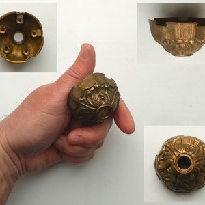Op de afbeelding: Een gouden metalen plafondarmatuur met een decoratief, versierd ontwerp. De armatuur heeft een ronde, gewelfde vorm met een centraal gat voor een lamp.