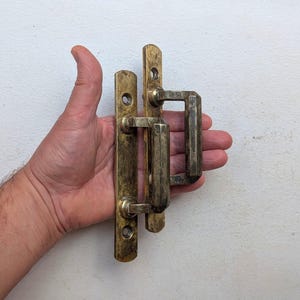 以下が含まれることがあります： アンティーク真鍮ドアハンドルセット。セットには、ハンドルとマッチするハンドルが付いた長方形のバックプレートが含まれています。真鍮は変色した外観で、古さを感じさせます。ハンドルは手で持たれています。
