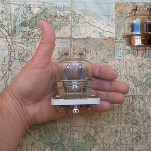 Puede incluir: Dos tubos de vacío de vidrio vintage con bases metálicas y tapas de color cobre. Los tubos se sostienen en una mano.