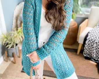 May include: A teal blue crochet cardigan with a lacy open stitch pattern. The cardigan is long and has a relaxed fit.