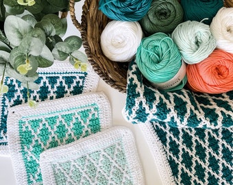 May include: Four crocheted dishcloths in shades of green and white. The dishcloths are made with a diamond pattern. There are also several balls of yarn in various shades of green, white, and red.