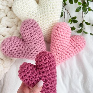 Pu&ograve; includere: Tre cuori all'uncinetto in diverse tonalit&agrave; di rosa e bianco. I cuori sono realizzati con un filato morbido e testurizzato e sono perfetti per una decorazione di San Valentino.