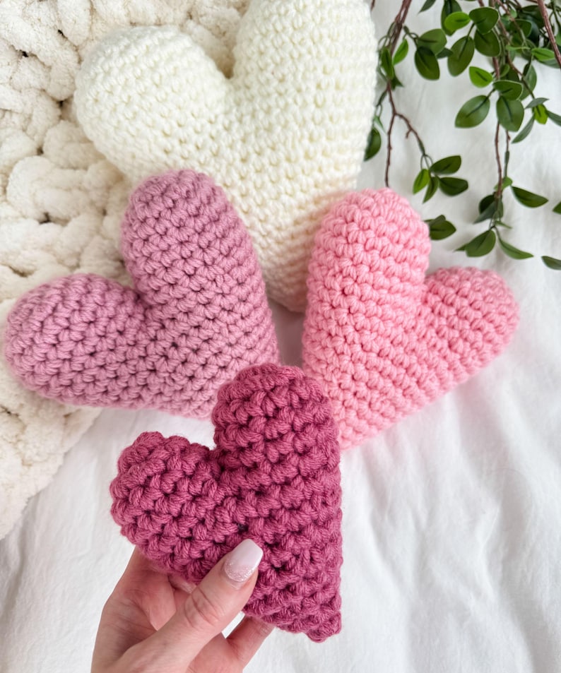Pu&ograve; includere: Tre cuori all'uncinetto in diverse tonalit&agrave; di rosa e bianco. I cuori sono realizzati con un filato morbido e testurizzato e sono perfetti per una decorazione di San Valentino.
