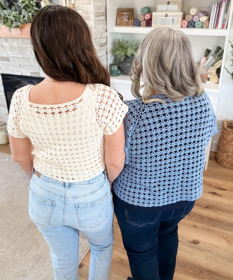 May include: Two women wearing handmade crochet tops. One top is cream-colored, the other is light blue. Both tops have a square neckline and short sleeves. The women are wearing jeans. The background includes a fireplace, shelves, and a wooden floor.
