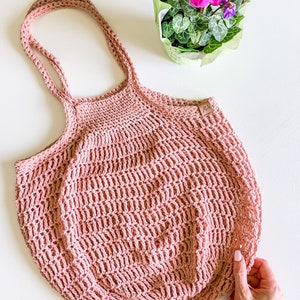May include: A pink crocheted tote bag with a brown leather tag that says "M&H".