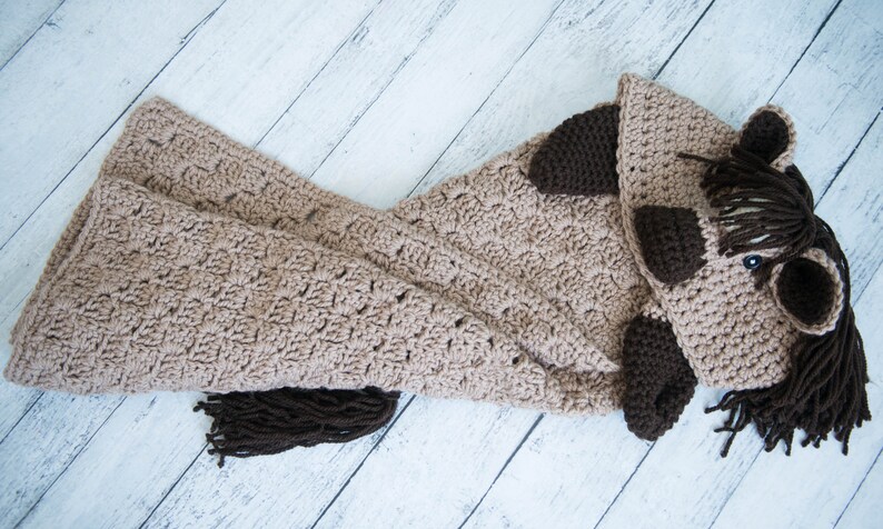 Pu&ograve; includere: Una coperta per cavallo in crochet marrone con una testa di cavallo in crochet marrone e una coda in crochet marrone.