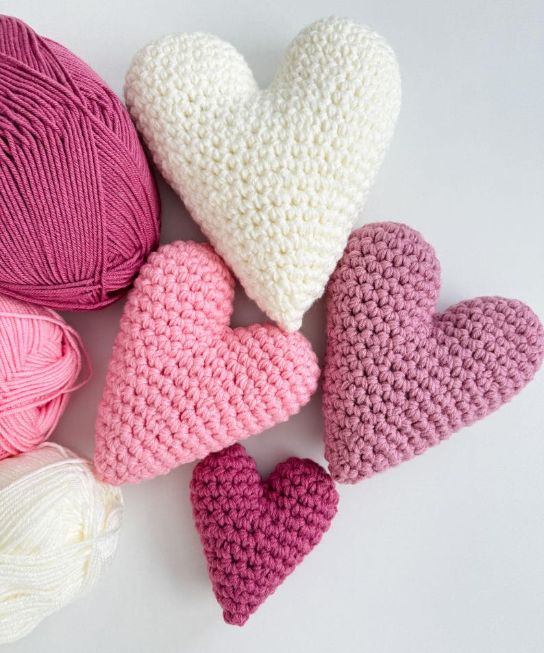 Pu&ograve; includere: Cinque cuori all'uncinetto in varie tonalit&agrave; di rosa e bianco. I cuori sono disposti in un gruppo, con il cuore pi&ugrave; grande al centro e il cuore pi&ugrave; piccolo in basso.