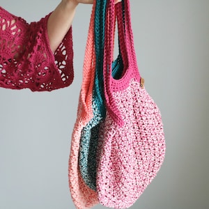 May include: Three crocheted tote bags in pink, teal and coral colours. The bags are made with a textured stitch and have a simple, minimalist design.