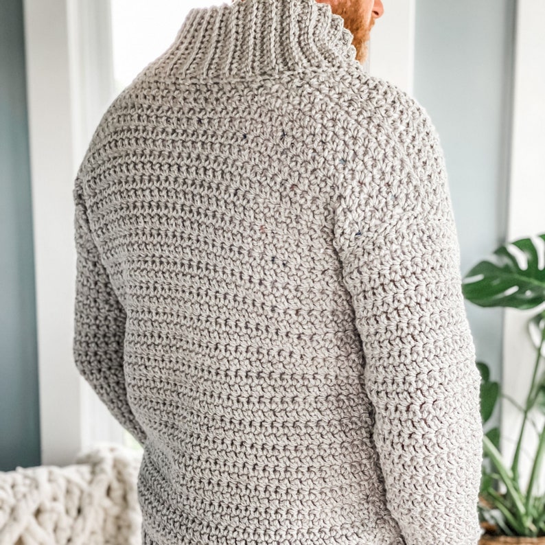 May include: A grey crocheted sweater with a high neck and long sleeves.