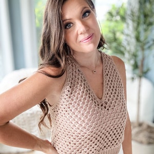 以下が含まれることがあります： Vネックの薄い茶色のクロシェの halter トップ。トップは繊細なオープンステッチパターンで作られています。