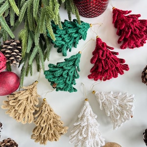 K&ouml;nnte beinhalten: Handgefertigte Weihnachtsbaumschmuck aus H&auml;kelarbeit in Gr&uuml;n, Rot, Beige und Wei&szlig;. Jeder Baum hat eine goldfarbene Spitze und eine Schlaufe zum Aufh&auml;ngen. Die Ornamente sind mit Tannenzapfen und Gr&uuml;n arrangiert.