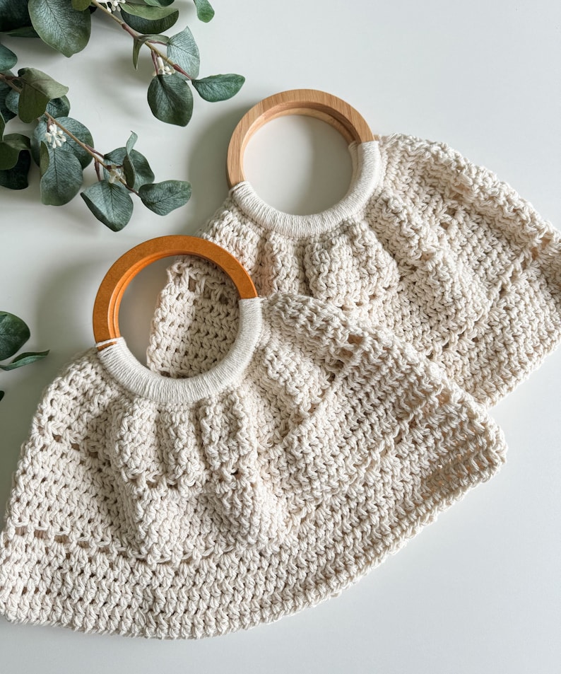 May include: Two crocheted bags with wooden handles. The bags are cream colored and have a textured, open weave pattern. The handles are natural wood.