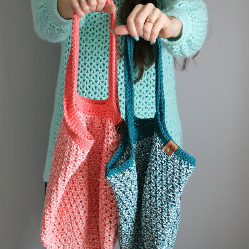 May include: Two crocheted tote bags, one in coral and one in teal, with a brown leather tag on the teal bag.