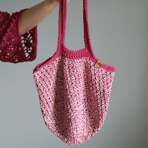 May include: A pink and white crocheted tote bag with a brown leather tag that says "Jell".