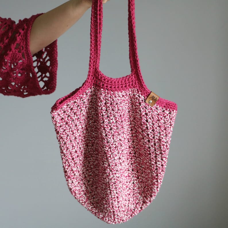 May include: A pink and white crocheted tote bag with a brown leather tag that says "Jell".