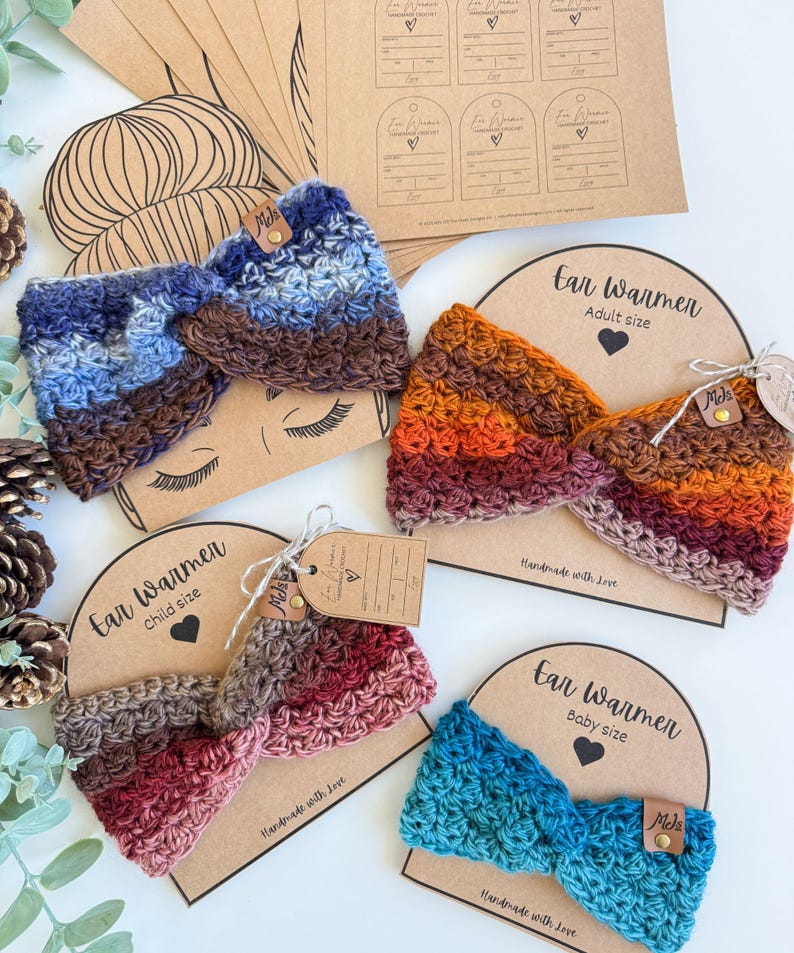 May include: A collection of handmade crochet ear warmers in various sizes and colors. The ear warmers are displayed on cardboard backing with the words "Ear Warmer" and size labels. Colors include blue, brown, red, and orange.