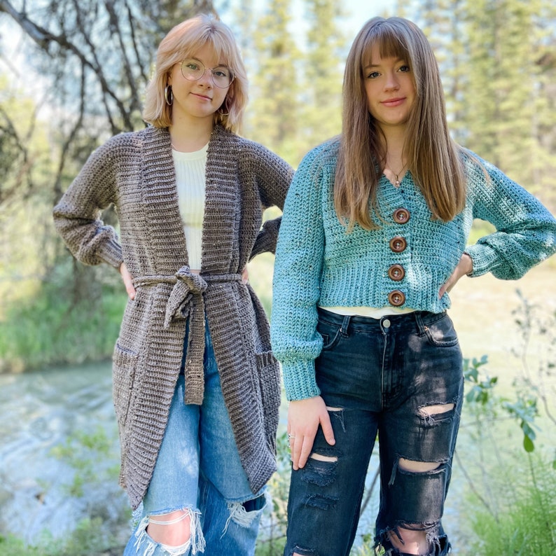 Op de afbeelding: Twee vrouwen dragen gebreide vesten. Een vest is bruin en lang, de andere is blauw en kort. Beide vrouwen dragen jeans.