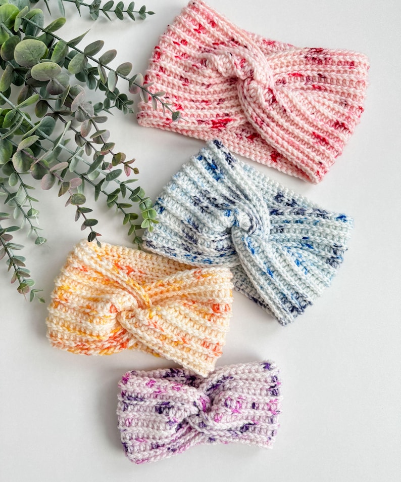 May include: Four crocheted headbands in different colors and patterns. The headbands are made with a twisted knot design. The colors are pink, blue, yellow, and purple.