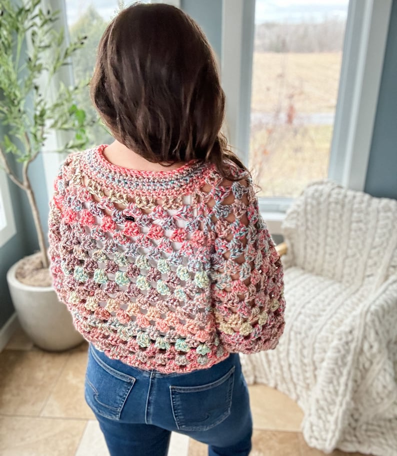 May include: A colorful crochet top with a loose, open-weave design. The top is made with a variety of shades of pink, blue, green, and beige yarn.