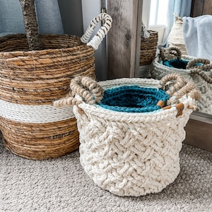 May include: Three woven baskets, one with a white and brown striped pattern, one with a teal liner, and one with a white braided pattern.