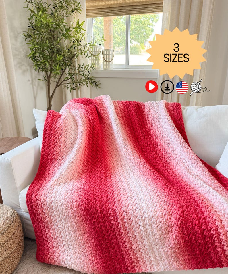 May include: A handmade, red and white ombre crochet blanket draped over a white sofa. The blanket features a textured stitch pattern and a gradient color scheme, transitioning from deep red to soft white. The image includes a text graphic that says "3 SIZES".