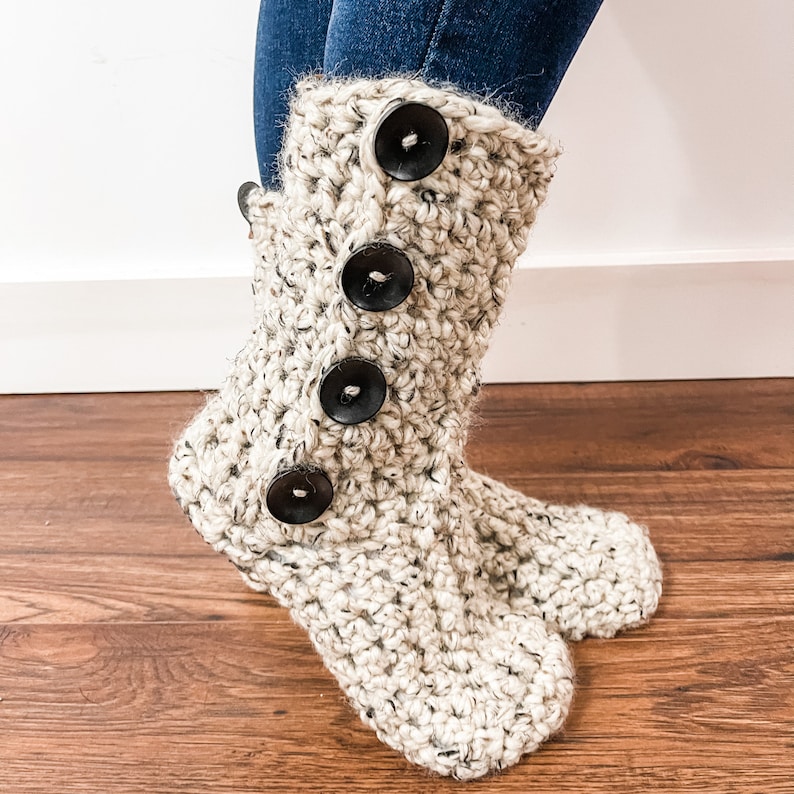 May include: Crocheted cream-coloured boot with black buttons. The boot is made with a chunky yarn and has a slouchy fit.