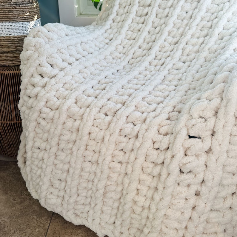 Peut inclure: Une couverture en tricot &eacute;pais de couleur blanc cr&egrave;me. La couverture est faite de fil &eacute;pais et a un motif tiss&eacute; textur&eacute;.