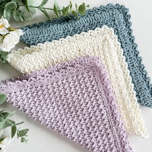 May include: Three crocheted squares in different colors: lavender, cream, and teal. Each square has a scalloped edge.