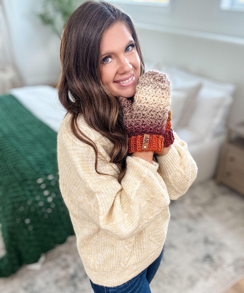 Peut inclure: Mitaines crochet&eacute;es &agrave; la main dans un d&eacute;grad&eacute; de cr&egrave;me, marron, bordeaux et orange. Les mitaines ont un poignet c&ocirc;tel&eacute; et une petite &eacute;tiquette en cuir. Les mitaines sont con&ccedil;ues pour la chaleur et le style.