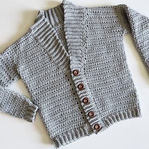 May include: A grey crocheted cardigan with a V-neck and wooden buttons.